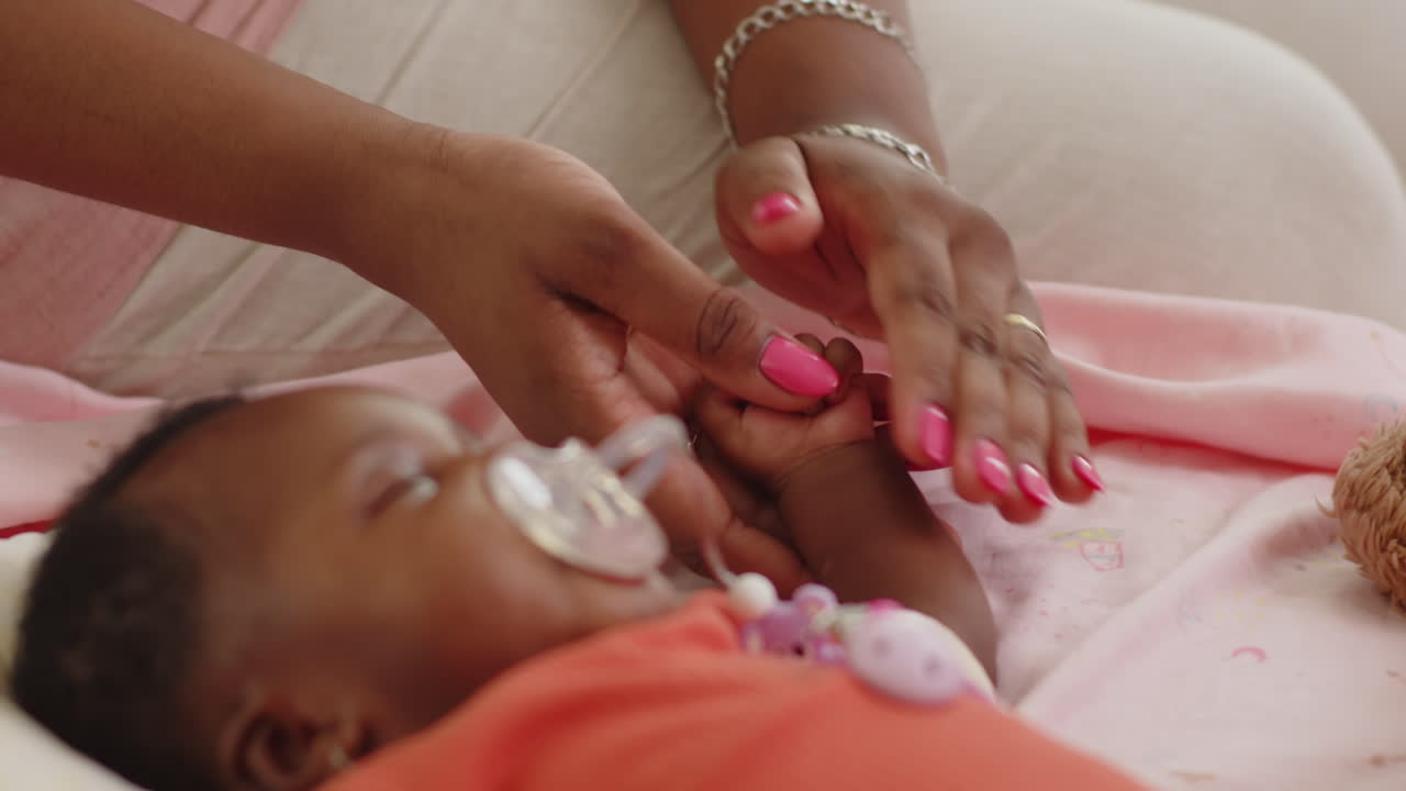 Happy Mother Stroking Hand of Sleeping Baby Girl