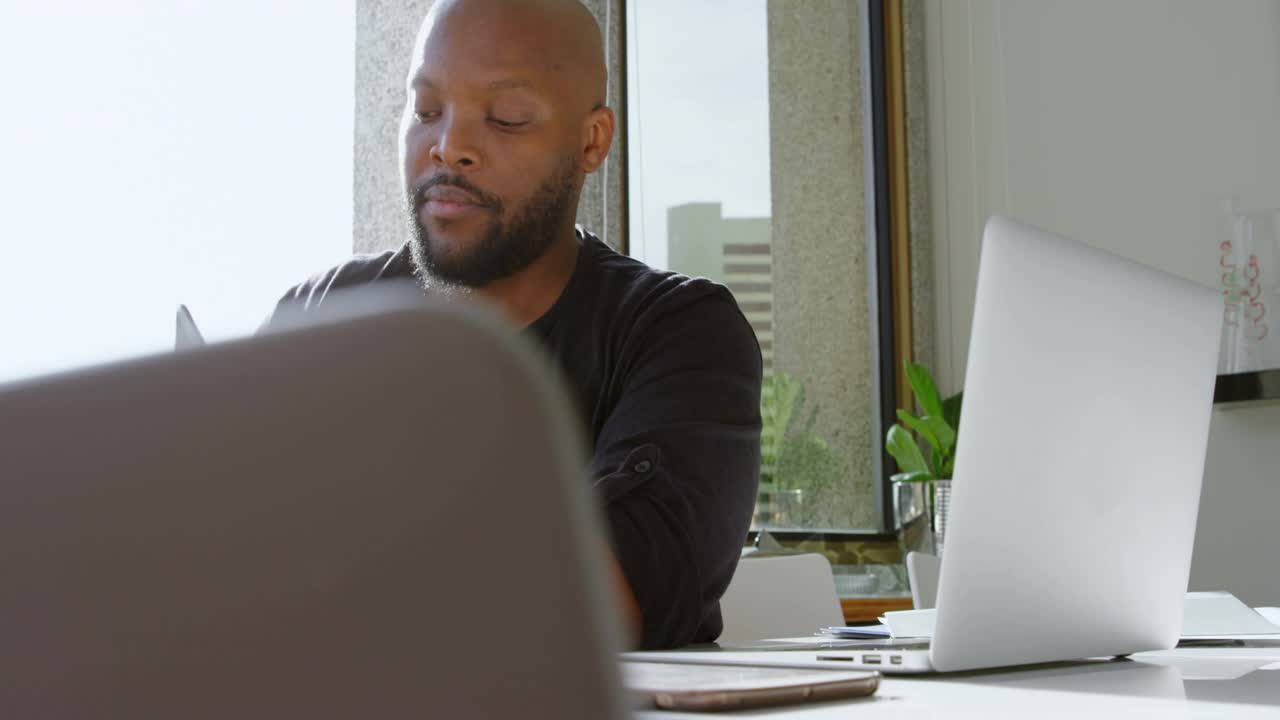 Man at desk tapping watch while holding phone, causing live alerts growing for social updates