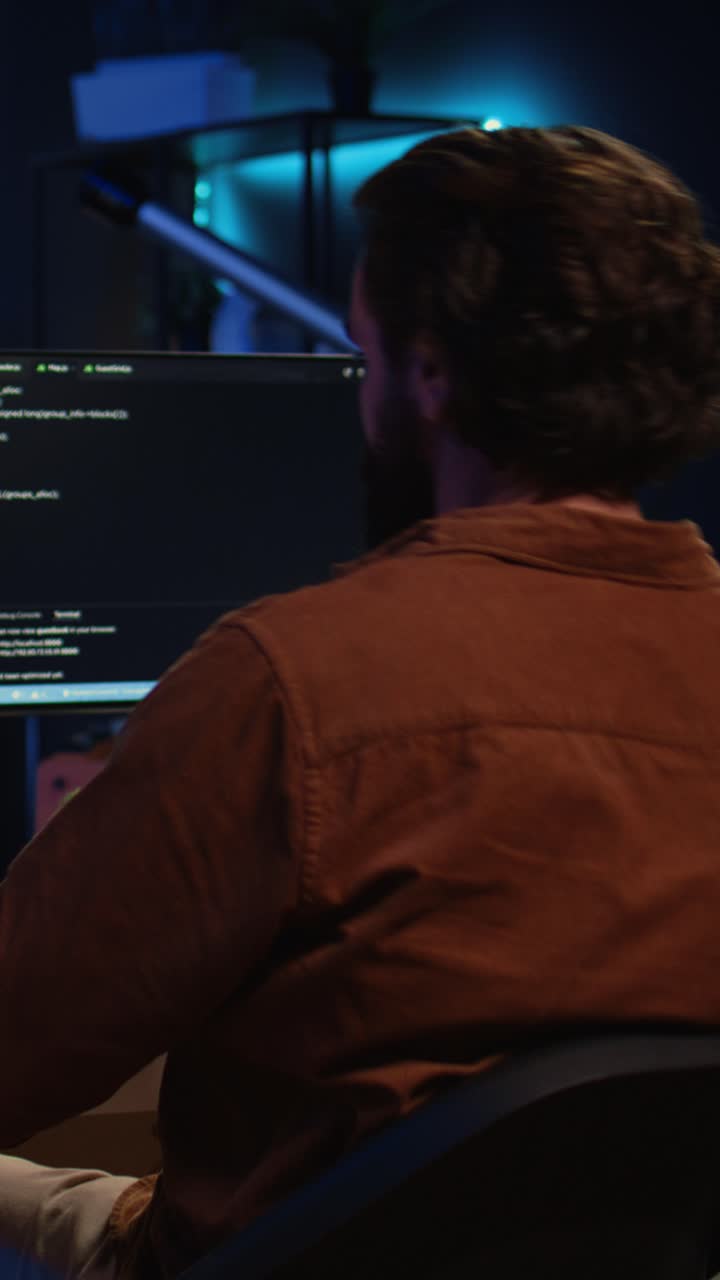 Man Walks to Desk and Starts Coding on Computer at Night