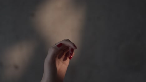 female hand playing with sunray in front of a concrete wall in slow motion and 4k at 25fps.