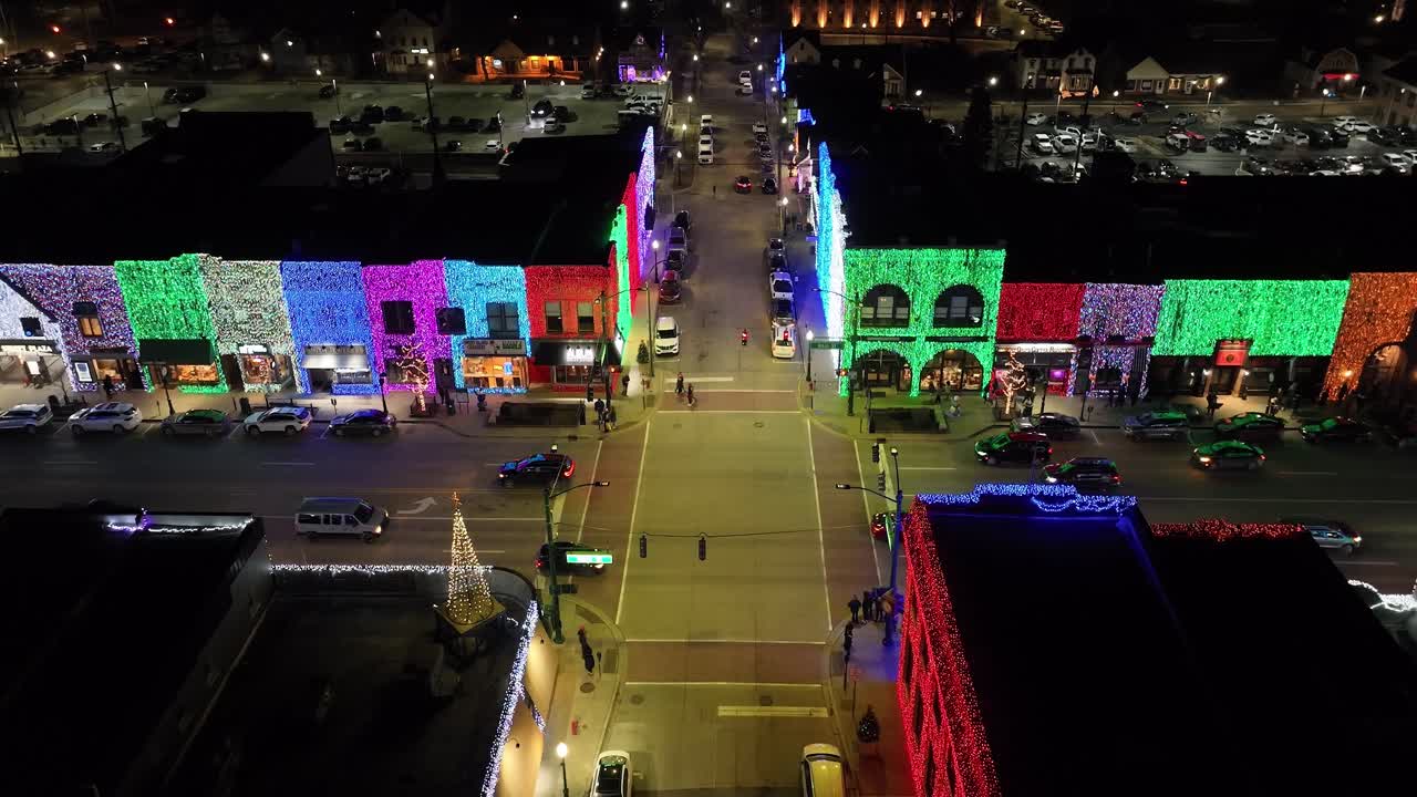 rochester, esquina de la calle michigan en la noche iluminada con luces navideñas en edificios junto con tráfico y video estable de drones