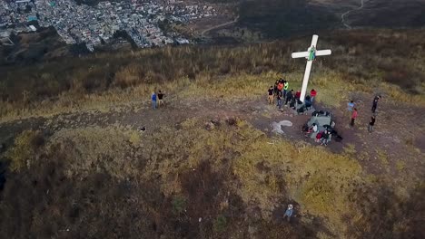 aerial view of people gathered around a cross on a hilltop
