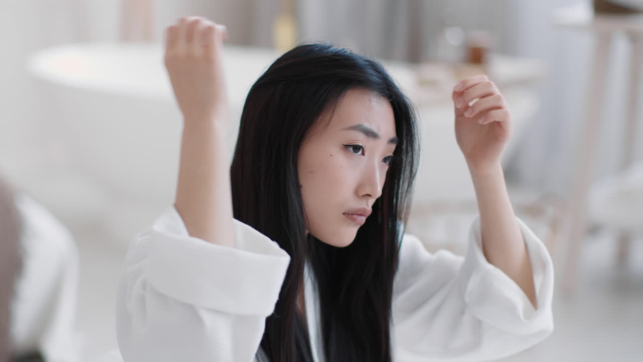 Woman checking her long hair in a bathroom
