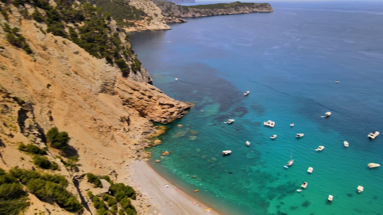 Coll Baix offers stunning turquoise waters and a serene atmosphere in Mallorca. Visitors enjoy sunbathing, swimming, and relaxing on the sandy shore surrounded by beautiful cliffs.