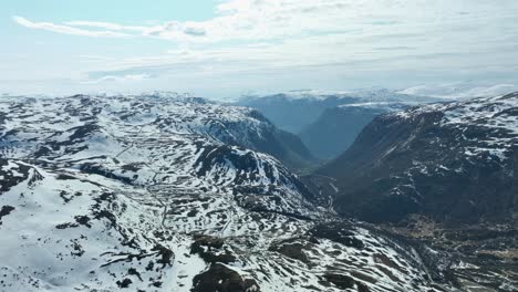 Sognefjellet-Gebirgspass,-Abstieg-Nach-Lustre-Und-Tindevegen-Gebirgspassstraße,-Die-Nach-Aardal-Führt,-Im-Linken-Bild-Zu-Sehen,-Wie-Sich-Die-Hügel-Hinauf-Winden-–-Luftbild