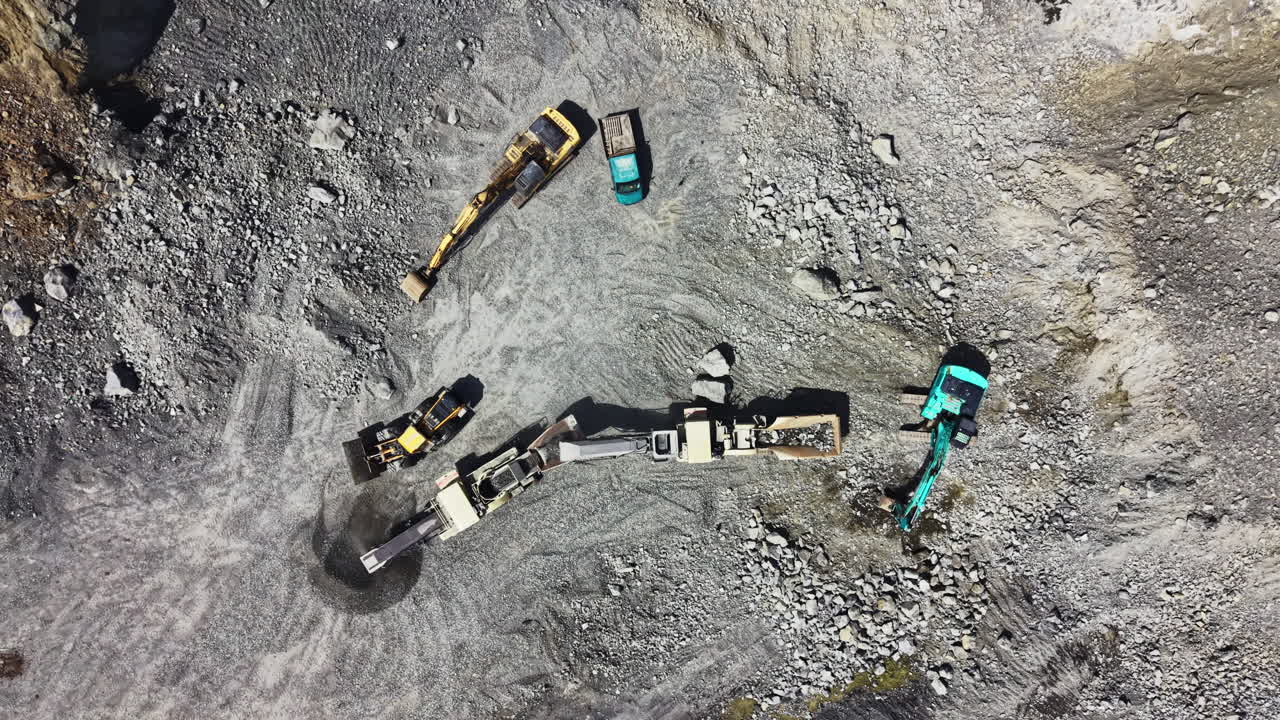 Granite quarry site with heavy machinery for rock extraction and processing during daylight hours