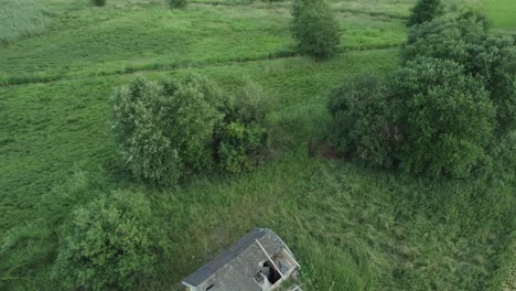 Aerial-drone-clip-over-a-dilapidated-house-in-the-countryside-during-summer