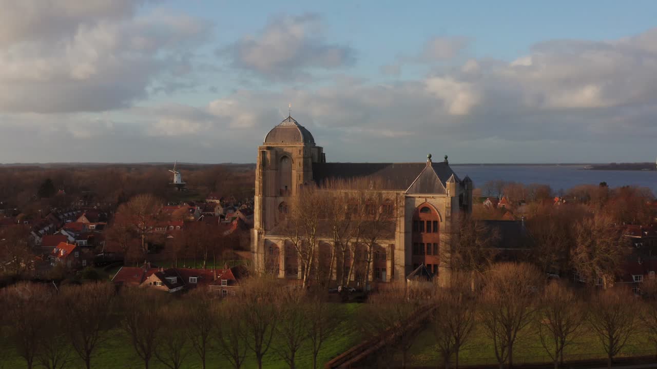 Revealing shot of the big Church of Veere from the canal. Orbital drone shot going away from the church