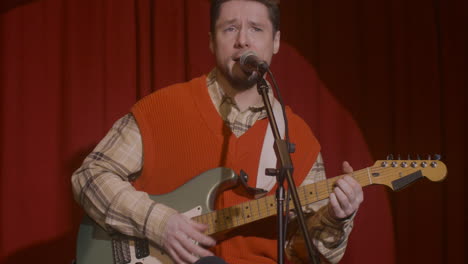 male musician playing guitar and singing during live music perfomance 1