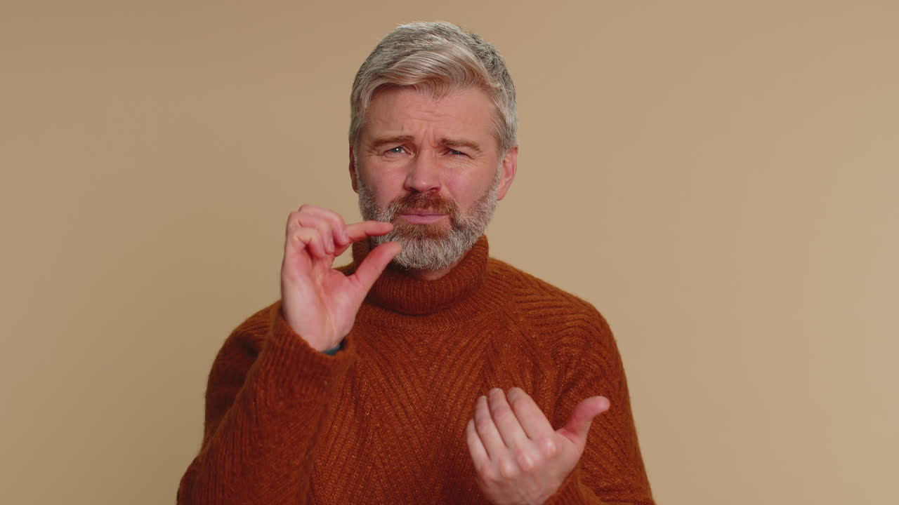 hombre mostrando un pequeño gesto con una sonrisa escéptica, mostrando un signo mínimo, midiendo tamaño pequeño