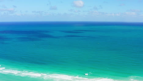 a serene drone fly-in captures the vast turquoise waters of the atlantic ocean gently meeting south beach’s white shore under a bright, clear sky.