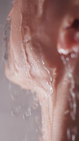 woman with water sprays on face in shower closeup. calm lady enjoys relaxing procedures in home bathroom. taking care of body and recreation