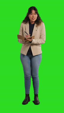 Vertikales-Video-Einer-Lehrerin-In-Einem-Klassenzimmer,-Die-Vor-Einem-Greenscreen-Hintergrund-Das-Klassenregister-Führt-2