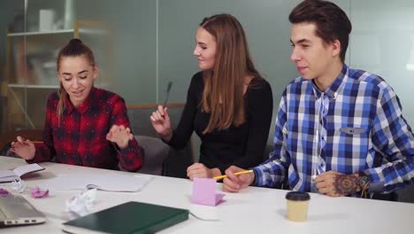 group of young creative workers in a creative start up work environment holding a project meeting in a conference room. discussing and crumpling papers, working hard before the deadline