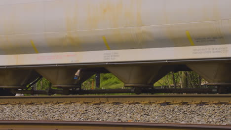 close-shot-of-wheels-of-a-hopper-car-a-tanker-and-a-boxcar-as-they-roll-across-the-rusty-railroad-tracks