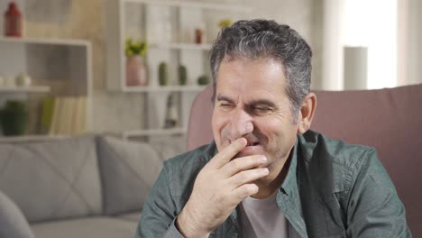 lonely man sitting on sofa at home and smiling to himself.