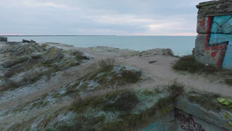 establishing aerial view of abandoned seaside fortification buildings at karosta northern forts on the beach of baltic sea , overcast day, wide drone shot moving forward