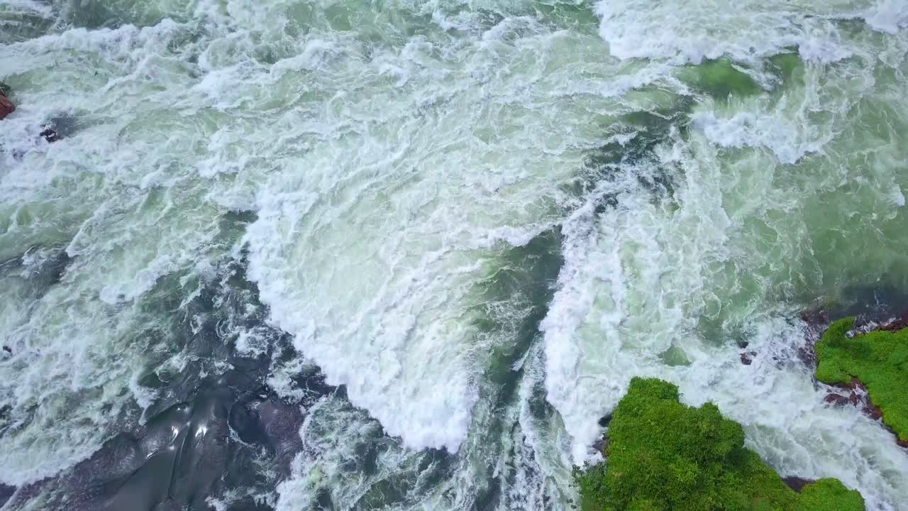 Showcasing the majestic River Nile as it flows through Uganda, Africa, creating breathtaking waterfalls and lush green islands, a testament to the raw beauty of nature, close up top down drone shot
