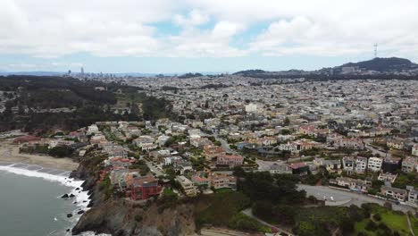 4k-30fps-Luftdrohnenaufnahmen-Der-Kalifornischen-Küste-In-Der-Nähe-Der-Klippenstadt-Und-Des-Strandes-Der-Presidio-Nachbarschaft-Mit-Der-Skyline-Von-San-Francisco-Im-Hintergrund,-Küstenwellen,-Die-Den-Sandstrand-In-China-Brechen