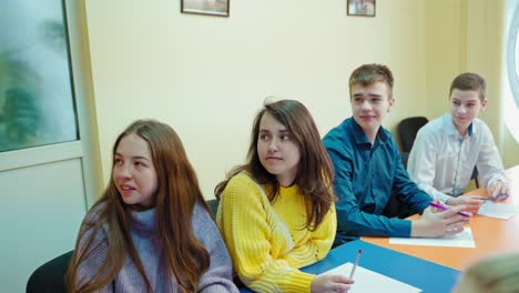 students studying in class. teenage boy answering the question. boys and girls sitting in the classroom and listening to their teacher at school.