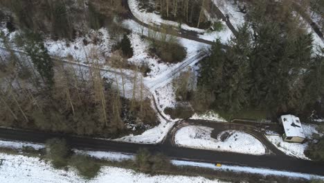 Snowy-rural-hazardous-remote-forest-road-aerial-snow-covered-woodland-tilt-up-across-countryside