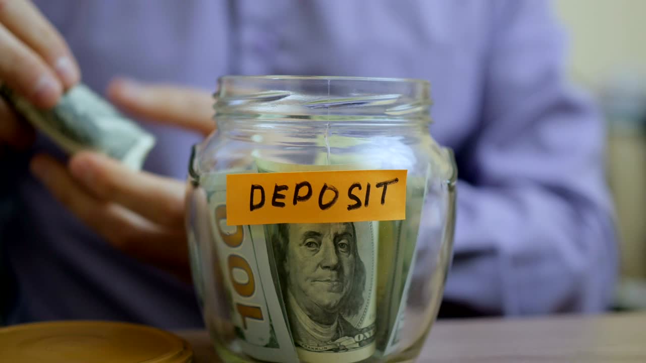 Caucasian man putting a glass jar put in a drawer table with his savings for future deposit
