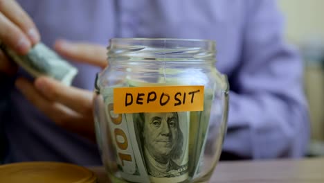 caucasian man putting a glass jar put in a drawer table with his savings for future deposit