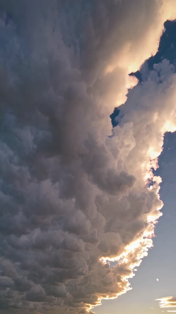 Dramatic upward angle captures towering clouds at sunset, showcasing their grandeur and dynamic