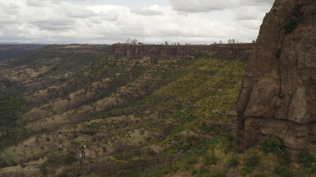 Aerial: California canyon valley reveal behind butte clifftop