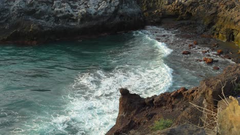 Waves-crashing-on-secluded-rocky-beach,-amidst-cliffs-in-Los-Gigantes