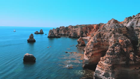 rocky cliffs and beautiful blue ocean during the summer in praia dona ana in the algarve in portugal, aerial drone view