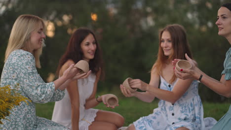 a group of young attractive women in nature in the field in the park sculpt from clay shape products decorate products communicate share impressions laugh rejoice at the results.