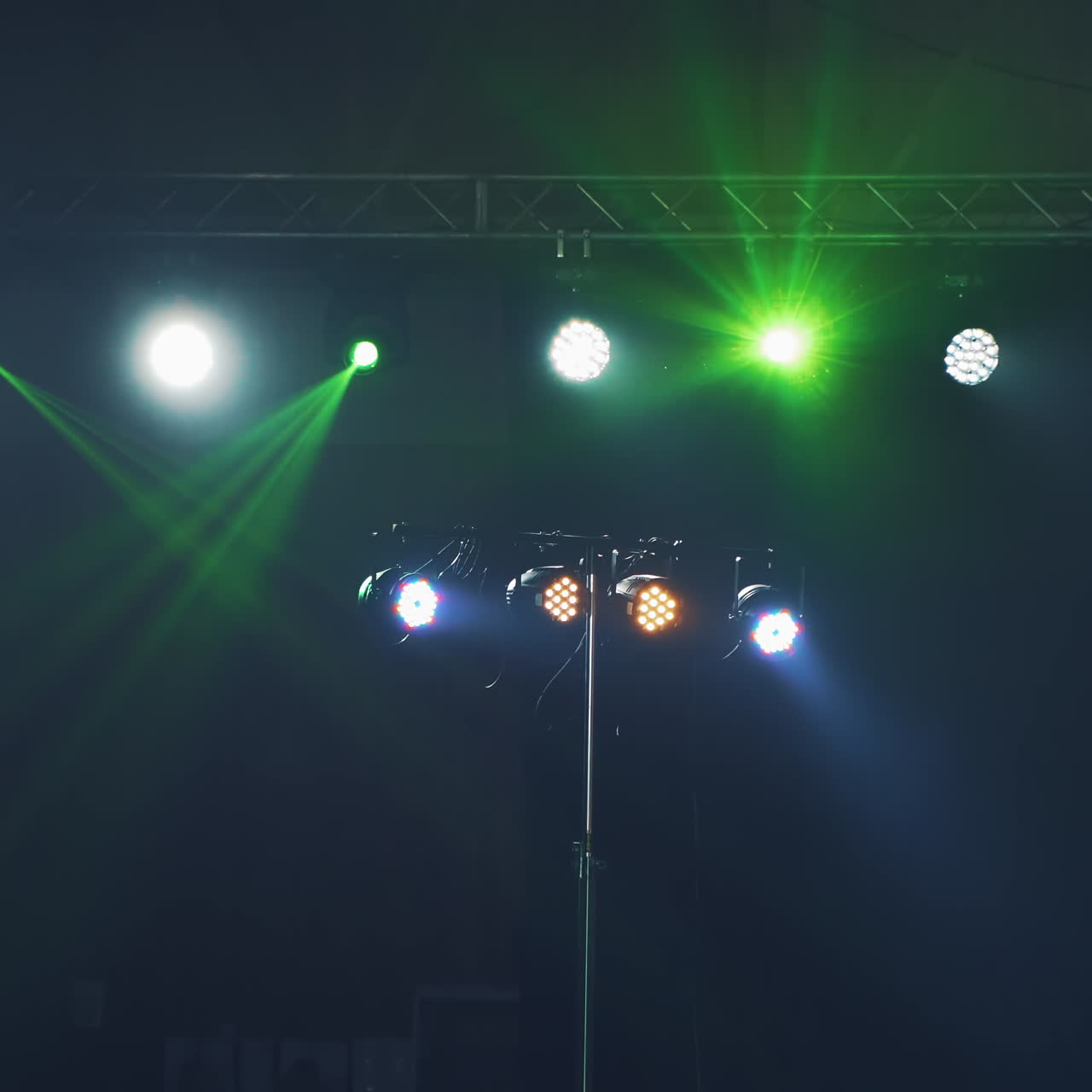 Colores brillantes de los proyectores cambiando sus luces en el escenario de la discoteca. Luces intermitentes brillan desde los focos durante un concierto musical en el interior.