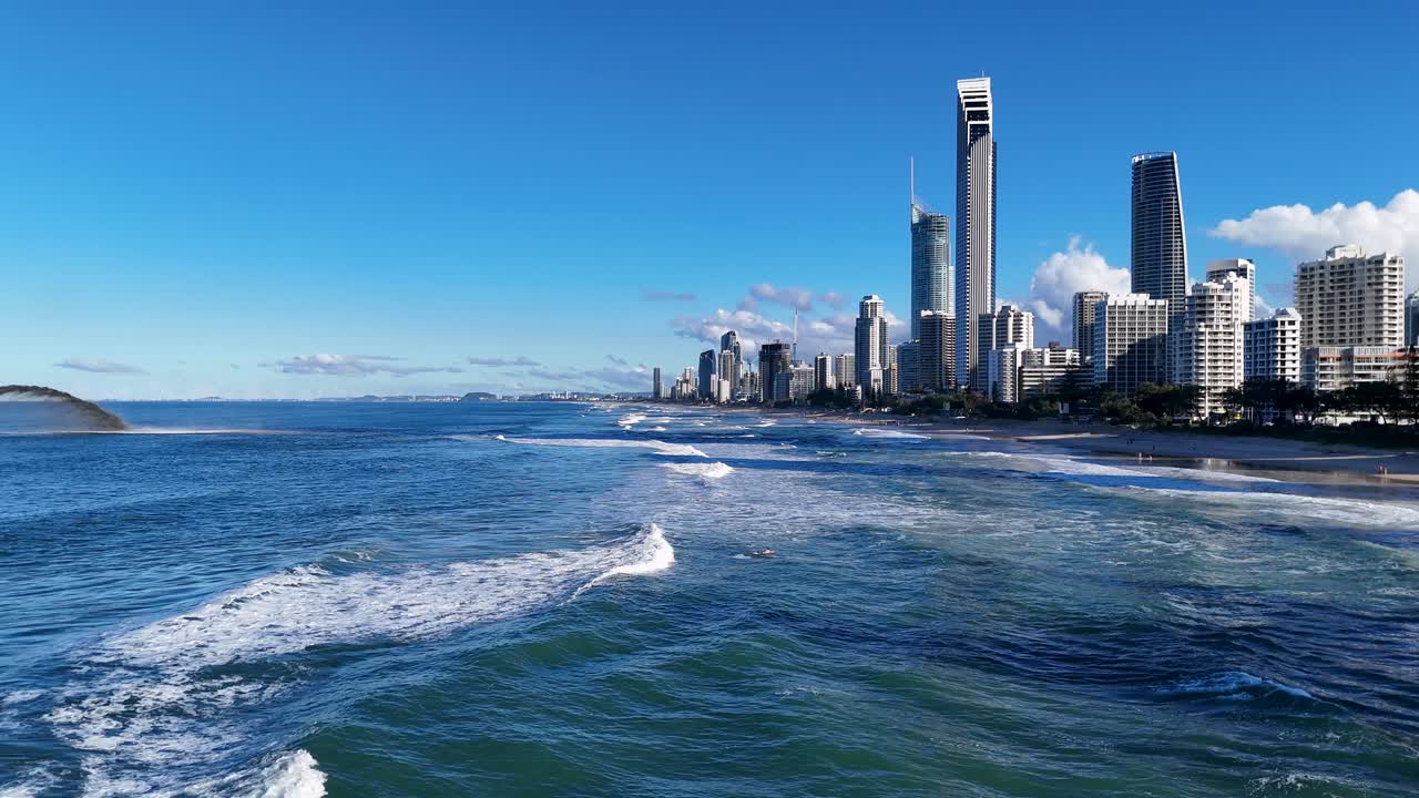 A dredger pumps sand near Surfers Paradise, Gold Coast, under clear blue skies with city skyline in the background