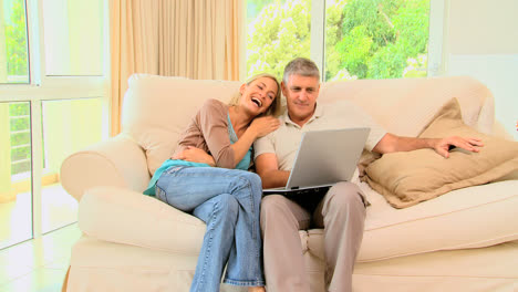pareja en el sofá disfrutando de un programa en su portátil