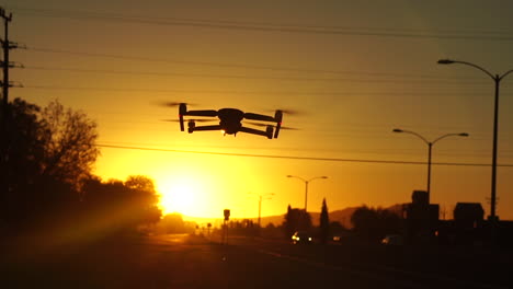 Drone-flying-and-hovering-with-golden-sunrise-or-sunset-background,-Slow-Motion