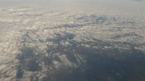 aerial view of clouds and greenery out of plane window shot in 4k high resolution