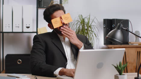 inefficient tired lazy business man working sleeping on laptop computer with eyes stickers on face