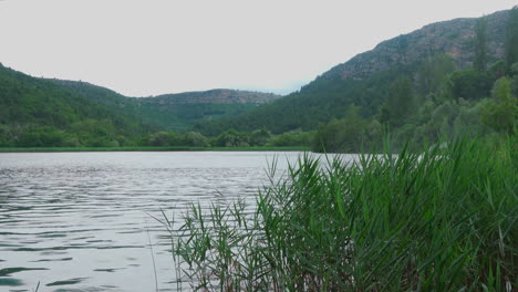 lake in krka national park with mountains and waterfall in the background