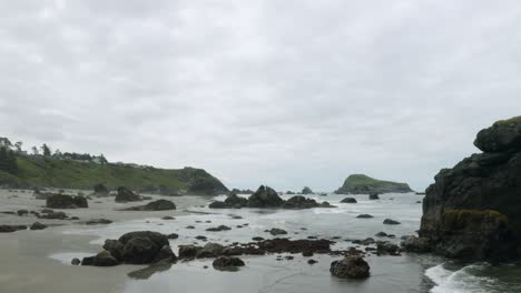 Rocks-scattered-on-a-sandy-beach-on-a-foggy-day,-Oregon-Beach