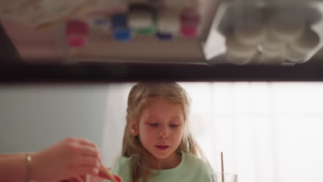 la niña mira a la hermana goteando pintura para el diseño de ebru