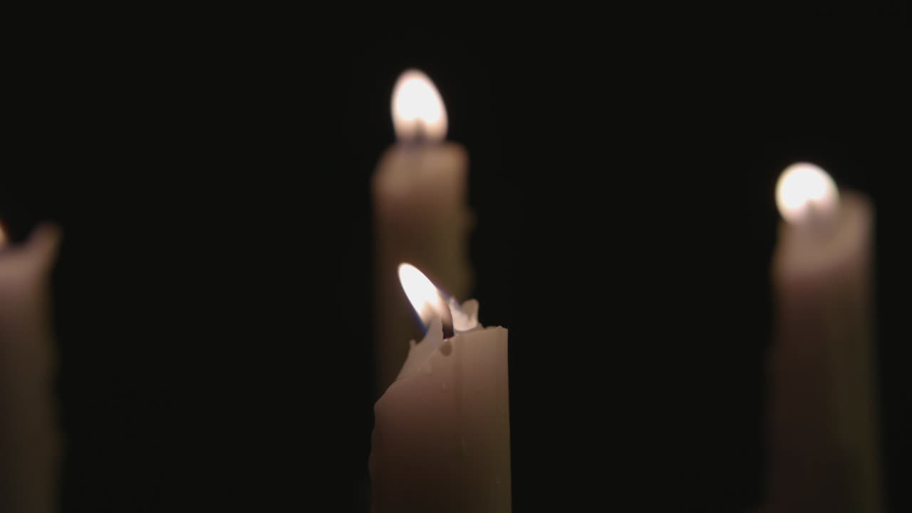 Quattro candele bianche accese, poi tre vengono spente dal vento al rallentatore.