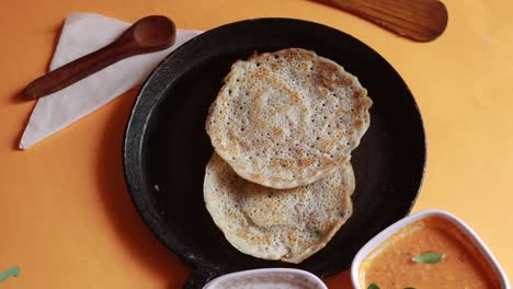 Rotierendes-Oothappam---Dosa---Südindisches-Frühstück-Mit-Reis,-Linsen-Und-Gemüse,-Serviert-Mit-Kokosnuss-Chutney,-Isoliert-Auf-Gelbem-Hintergrund