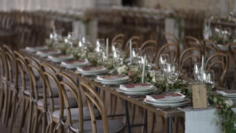 long, elegantly set wedding tables with floral centerpieces and wooden chairs in a reception hall