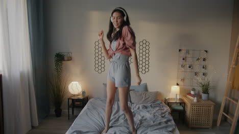 woman dancing on a bed with headphones