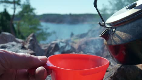 Pouring-hot-steaming-coffee-into-mug-in-the-outdoors