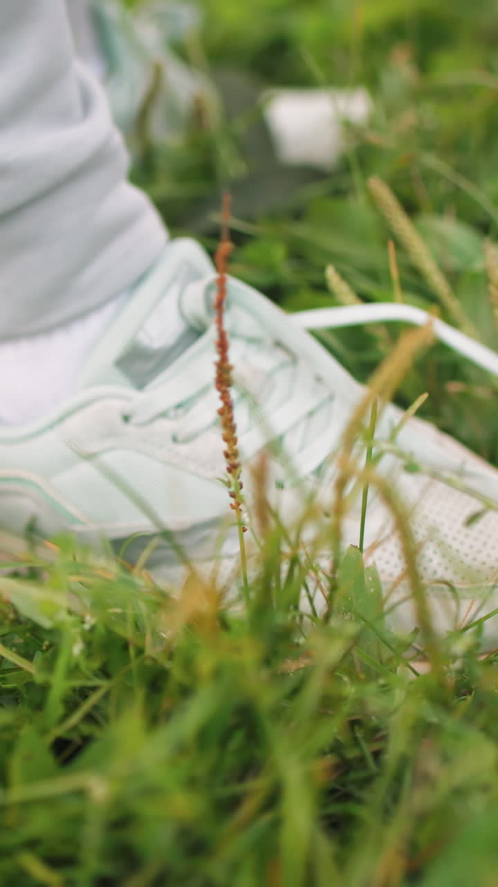 클로버 밭에서 민트색 운동화 끈을 묶는 모습이 클로즈업으로 자세히 보이고, 부드러운 손과 하얀 손톱, 은은한 햇빛과 이슬, 여유로운 산책 전의 평온한 순간, 그리고 사색적이고 고요한 분위기가 느껴져요.