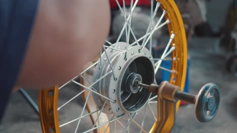 technician man working motorcycle wheel has spokes weave up on mechanic tool new steel wheel