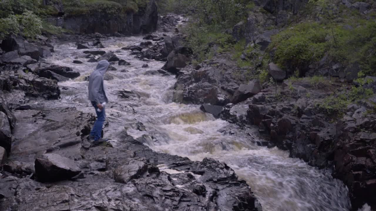 한 남자가 산 강에서 물을 마시고 있다
