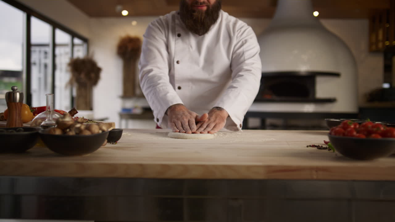 Un panettiere impasta l'impasto in cucina. Lo chef prepara pizza e pane in un ristorante.